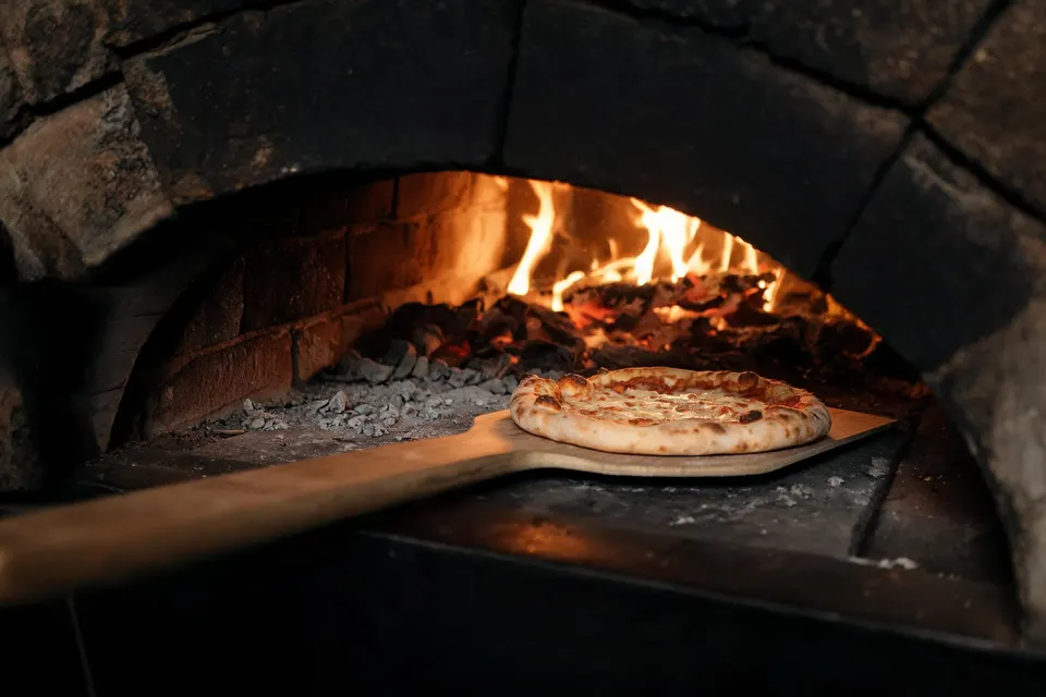 Frisch gebackene Pizza vor dem warmen Feuerschein des Ofens